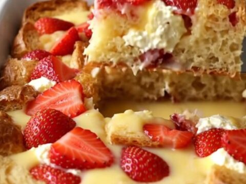 A golden, baked French toast dish with visible strawberry slices and cream cheese pockets.