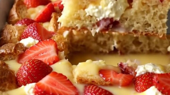 A golden, baked French toast dish with visible strawberry slices and cream cheese pockets.
