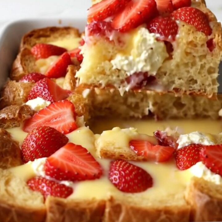A golden, baked French toast dish with visible strawberry slices and cream cheese pockets.