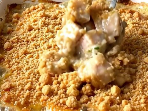 A top-down view of a rectangular white baking dish filled with golden-brown chicken pieces and a crispy crumb topping.