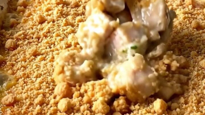 A top-down view of a rectangular white baking dish filled with golden-brown chicken pieces and a crispy crumb topping.