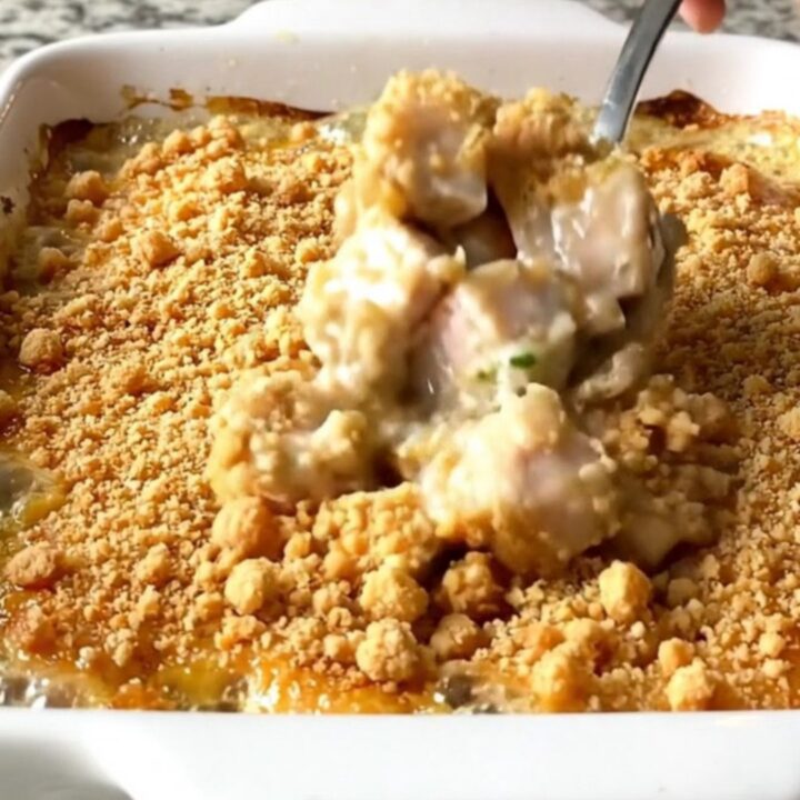 A top-down view of a rectangular white baking dish filled with golden-brown chicken pieces and a crispy crumb topping.