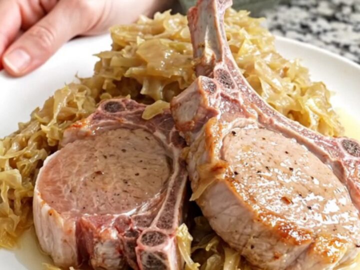 Four bone-in pork chops fanned out in a black slow cooker with sauerkraut and apple juice.