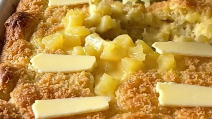 A golden, bubbling pineapple bread stuffing bake in a white ceramic dish on a light countertop.