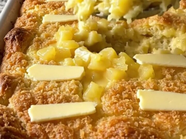 A golden, bubbling pineapple bread stuffing bake in a white ceramic dish on a light countertop.