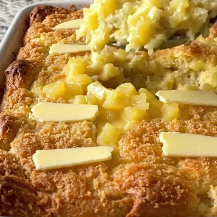 A golden, bubbling pineapple bread stuffing bake in a white ceramic dish on a light countertop.