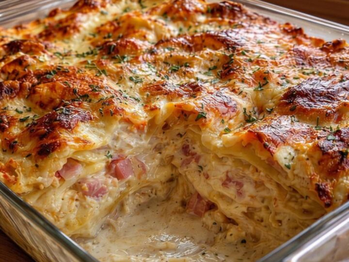 A steaming, freshly baked chicken cordon bleu lasagna in a glass dish with a melted, bubbly Swiss cheese top.