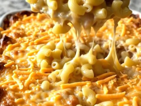 A top-down view of a rectangular baking dish filled with elbow macaroni, turkey meatballs, and melted sharp cheddar cheese.