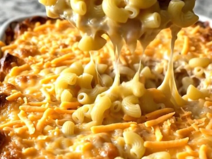 A top-down view of a rectangular baking dish filled with elbow macaroni, turkey meatballs, and melted sharp cheddar cheese.
