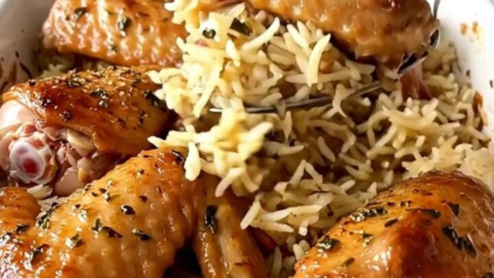 A ceramic baking dish filled with golden-brown turkey wings and fluffy herb-infused rice.