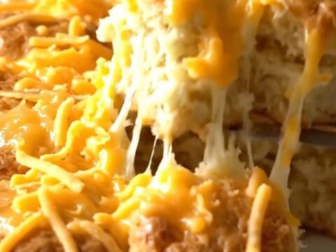 A golden brown pull-apart biscuit bake with melted sharp cheddar cheese in a rectangular white baker.