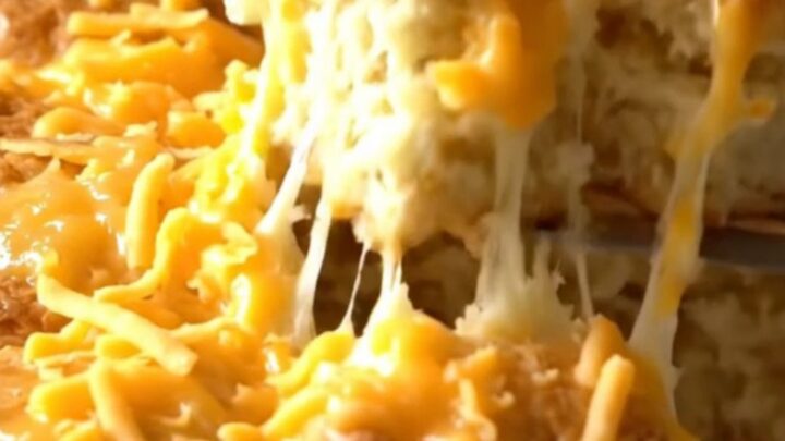 A golden brown pull-apart biscuit bake with melted sharp cheddar cheese in a rectangular white baker.
