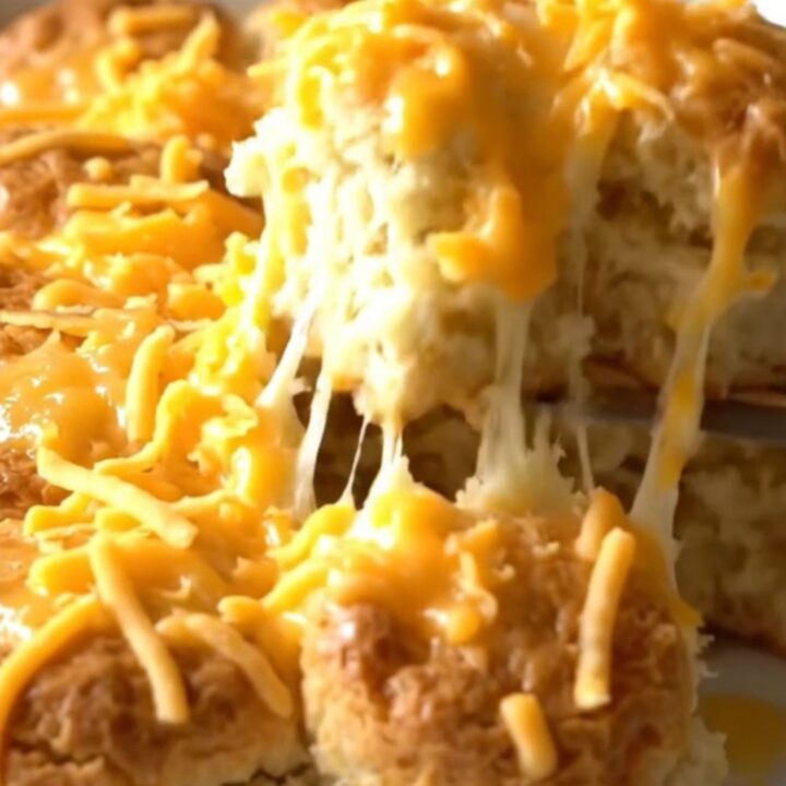 A golden brown pull-apart biscuit bake with melted sharp cheddar cheese in a rectangular white baker.
