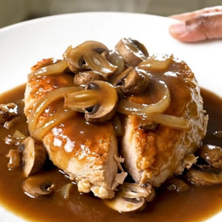Slow cooker steakhouse mushroom chicken served on a white plate with a rich gravy.