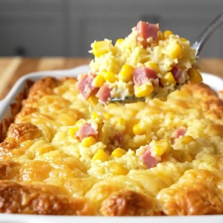 A top-down view of a rectangular baking dish filled with a golden, baked ham and cheddar corn pudding casserole.
