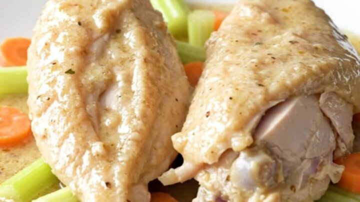 A slow cooker filled with chicken breasts, carrots, celery, and creamy soup before being cooked.
