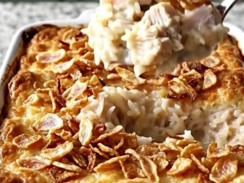 A top-down view of a rectangular baking dish filled with creamy chicken and rice, topped with crispy onions.