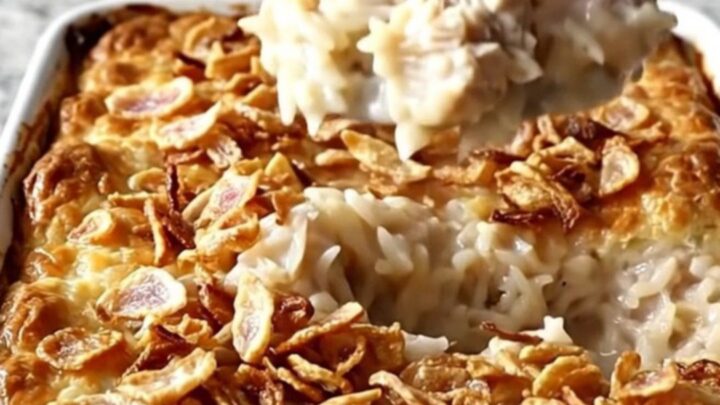 A top-down view of a rectangular baking dish filled with creamy chicken and rice, topped with crispy onions.