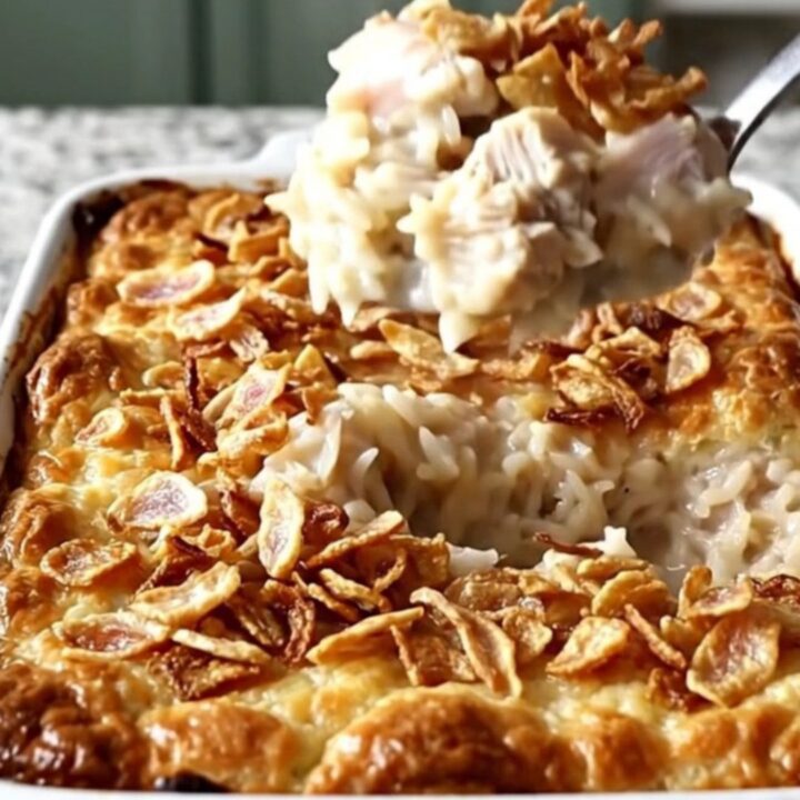 A top-down view of a rectangular baking dish filled with creamy chicken and rice, topped with crispy onions.