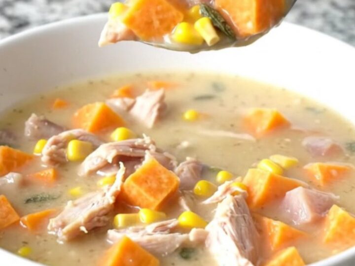 A steaming bowl of creamy turkey and sweet potato chowder with visible corn and sage.
