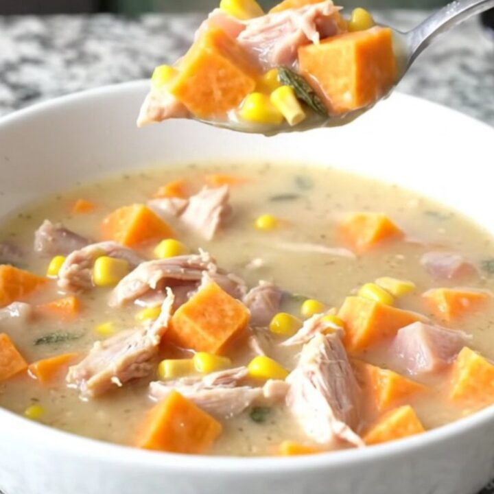 A steaming bowl of creamy turkey and sweet potato chowder with visible corn and sage.