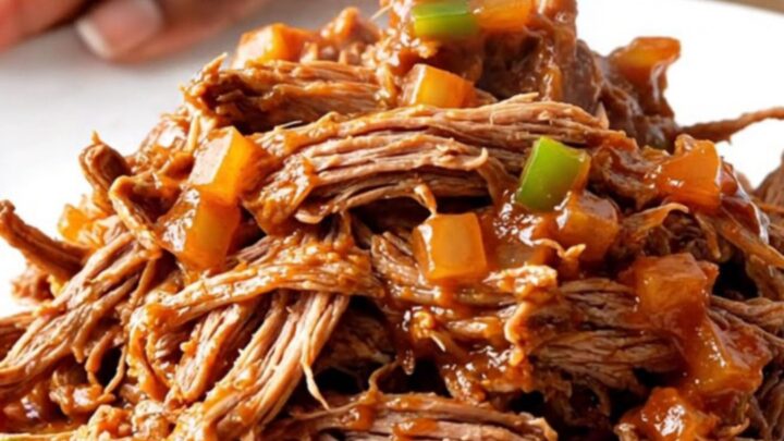 A close-up of a portion of slow cooker pot roast sloppy joes on a white plate.