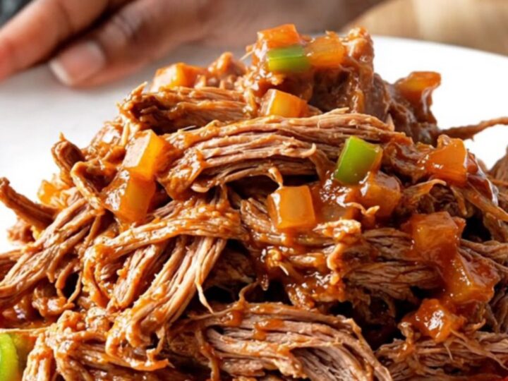 A close-up of a portion of slow cooker pot roast sloppy joes on a white plate.