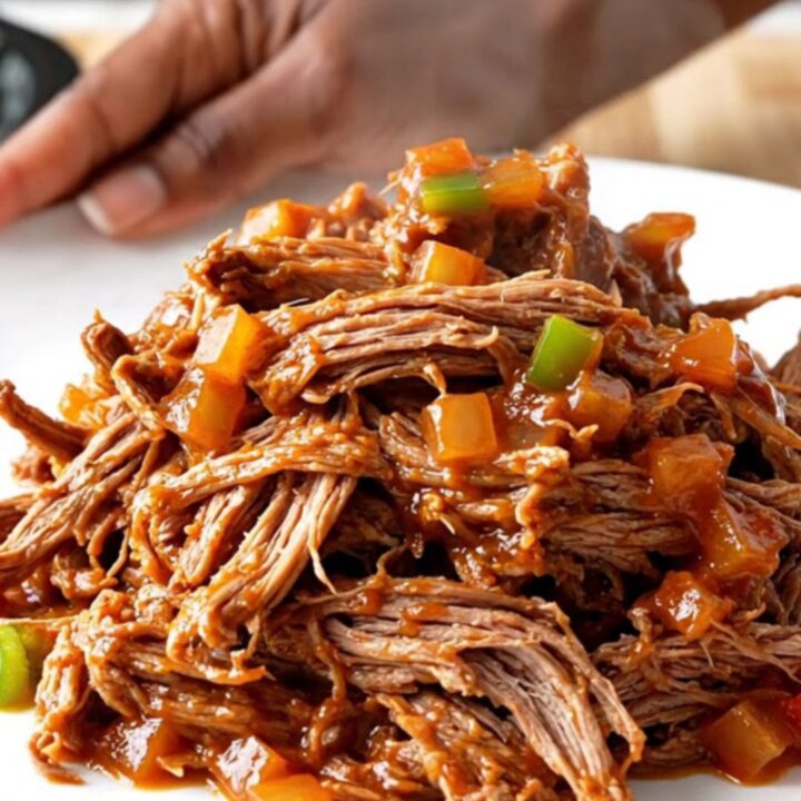 A close-up of a portion of slow cooker pot roast sloppy joes on a white plate.