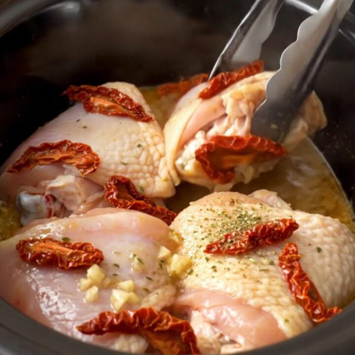 A top-down view of tender, braised chicken thighs in a slow cooker