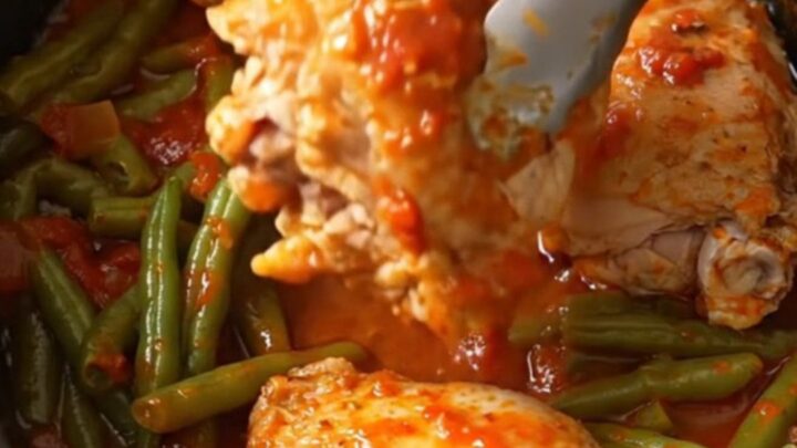 A bowl of slow-cooked chicken thighs with green beans in a rich tomato sauce.