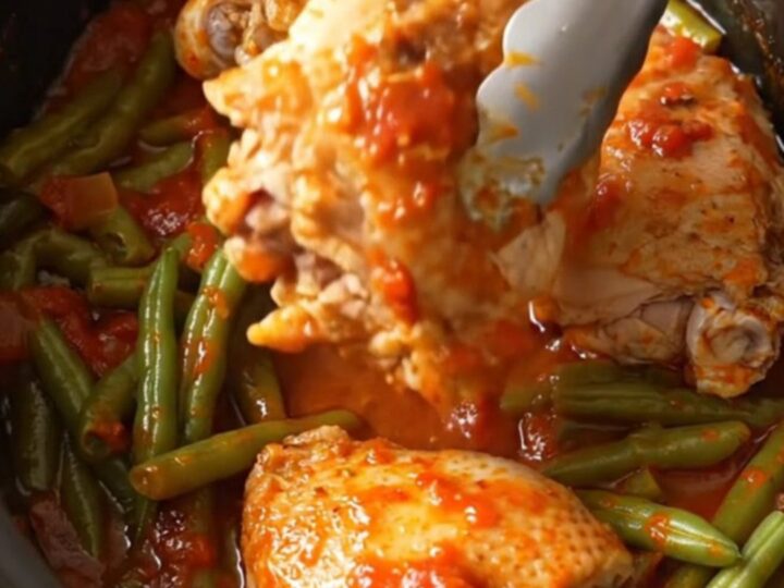A bowl of slow-cooked chicken thighs with green beans in a rich tomato sauce.