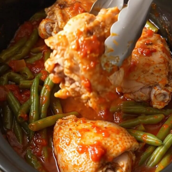 A bowl of slow-cooked chicken thighs with green beans in a rich tomato sauce.