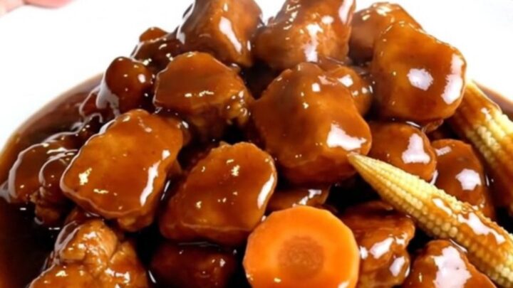 A close-up of slow cooker Hunan chicken with carrots and baby corn in a rich sauce.