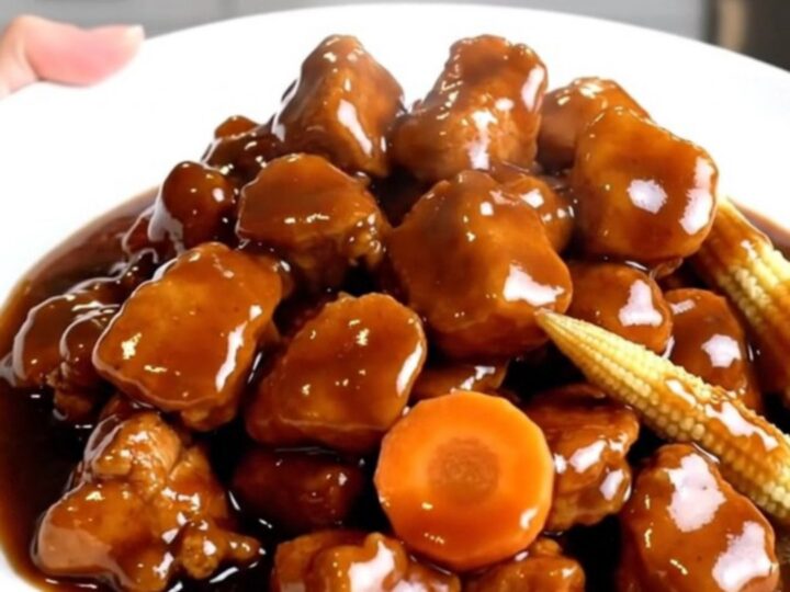 A close-up of slow cooker Hunan chicken with carrots and baby corn in a rich sauce.
