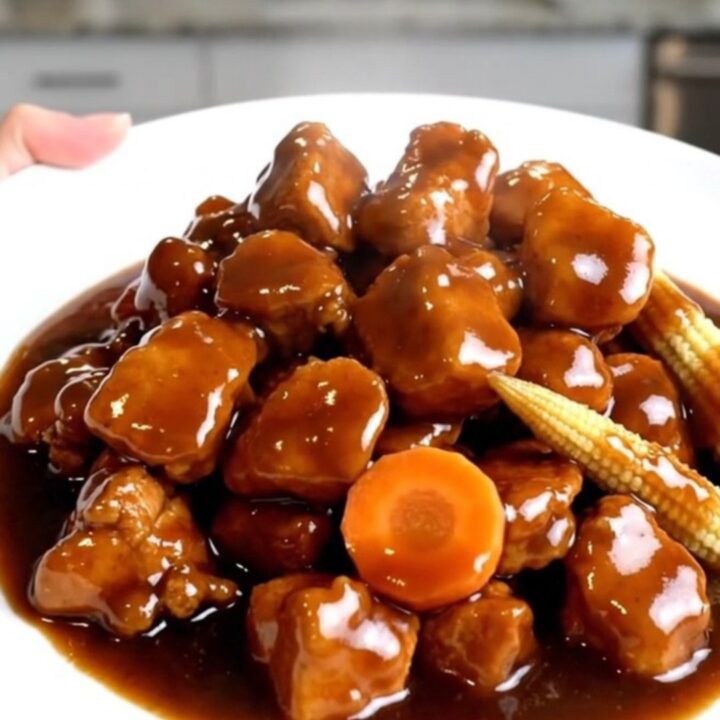 A close-up of slow cooker Hunan chicken with carrots and baby corn in a rich sauce.
