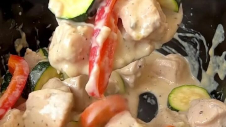 Creamy crockpot chicken primavera served in a bowl, showcasing chicken, zucchini, peppers, and carrots in a rich sauce.