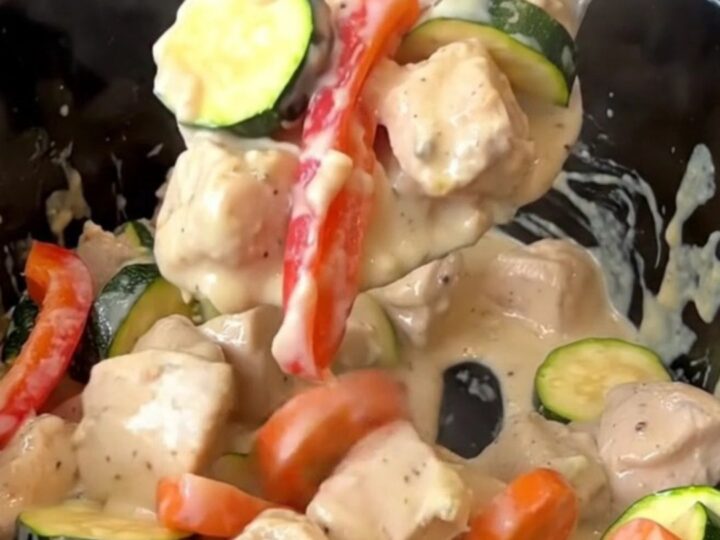 Creamy crockpot chicken primavera served in a bowl, showcasing chicken, zucchini, peppers, and carrots in a rich sauce.
