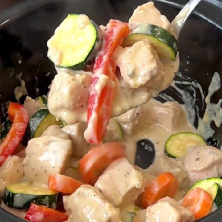 Creamy crockpot chicken primavera served in a bowl, showcasing chicken, zucchini, peppers, and carrots in a rich sauce.