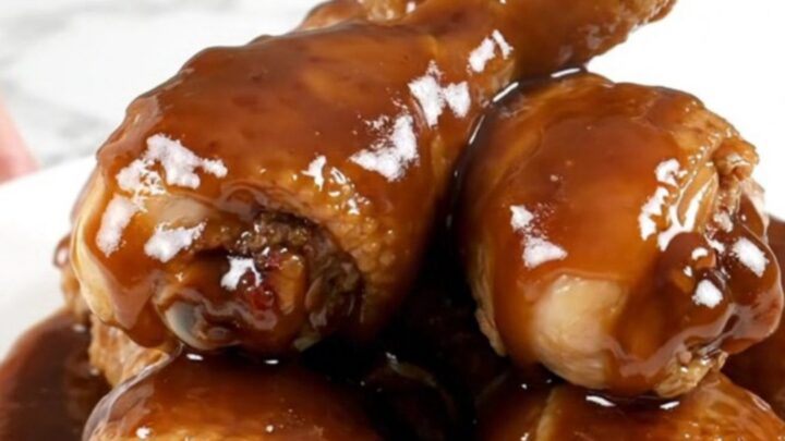 Close up of slow-cooked molasses barbecue chicken drumsticks in a black ceramic slow cooker pot.