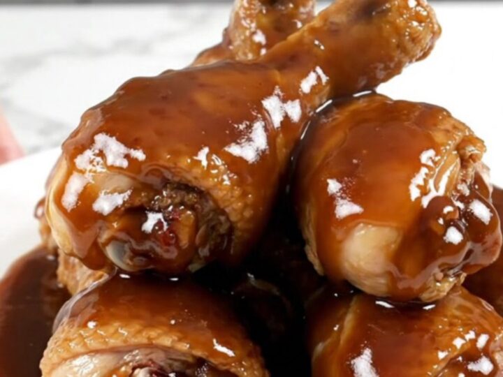 Close up of slow-cooked molasses barbecue chicken drumsticks in a black ceramic slow cooker pot.
