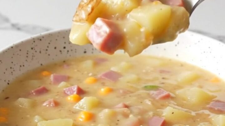 A steaming bowl of creamy jalapeno popper ham chowder topped with shredded cheddar and fresh jalapeno slices.