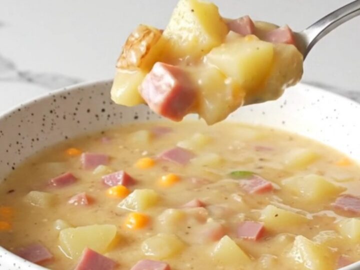 A steaming bowl of creamy jalapeno popper ham chowder topped with shredded cheddar and fresh jalapeno slices.