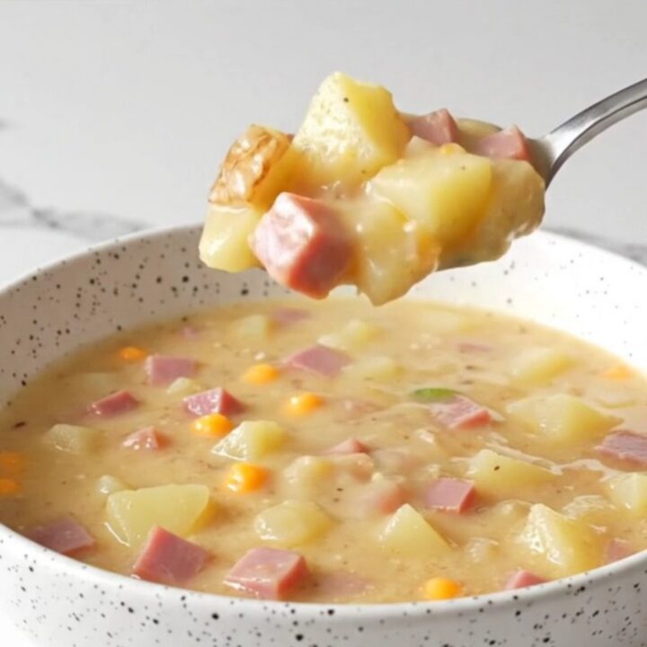 A steaming bowl of creamy jalapeno popper ham chowder topped with shredded cheddar and fresh jalapeno slices.