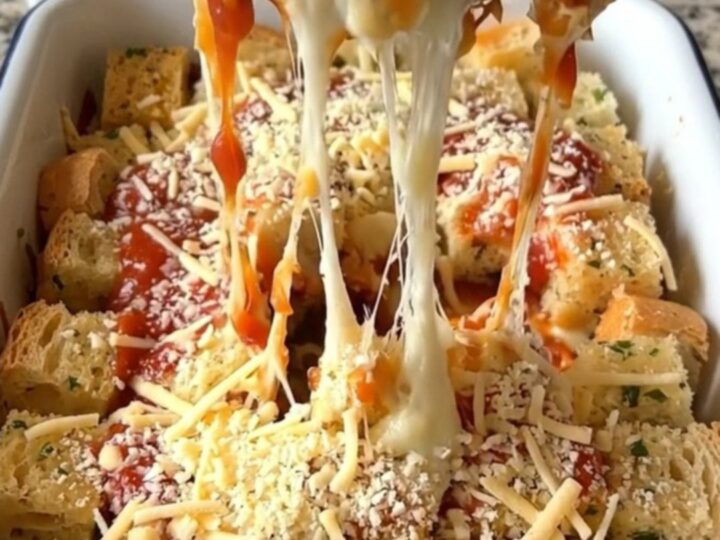 A top-down view of a rectangular baker filled with golden-brown garlic bread pizza bake, featuring bubbling cheese.