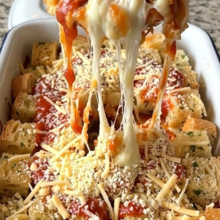 A top-down view of a rectangular baker filled with golden-brown garlic bread pizza bake, featuring bubbling cheese.