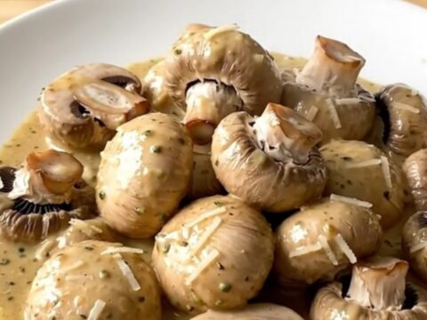 Creamy garlic parmesan mushrooms served in a white bowl with a rich, white sauce.