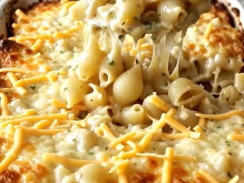 A top-down view of a rectangular baking dish filled with dry pasta shells and creamy garlic herb sauce.
