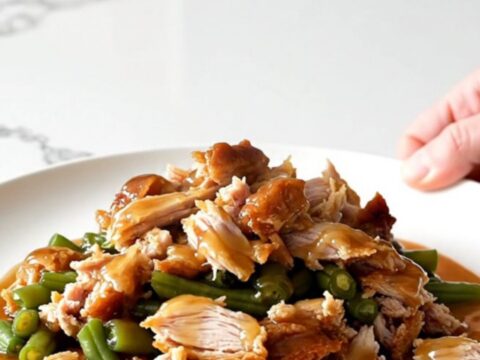 A white plate filled with cooked ground turkey and green beans glazed in a shiny honey garlic sauce.