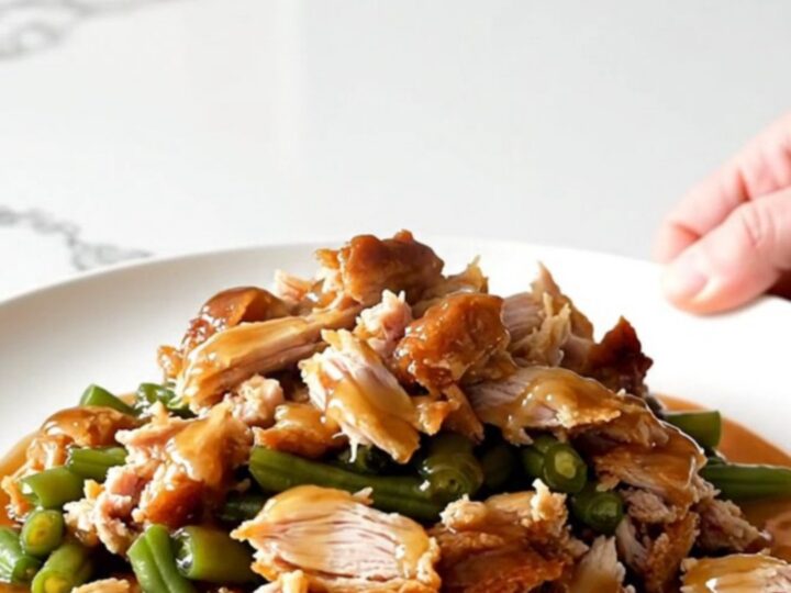 A white plate filled with cooked ground turkey and green beans glazed in a shiny honey garlic sauce.