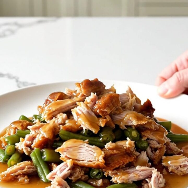 A white plate filled with cooked ground turkey and green beans glazed in a shiny honey garlic sauce.